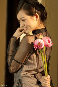 Close-up of smiling young woman standing by roses
