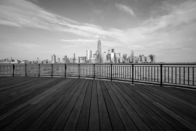 Boardwalk by sea against sky in city