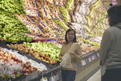 View of couple standing in supermarkets and talking while choosing apples