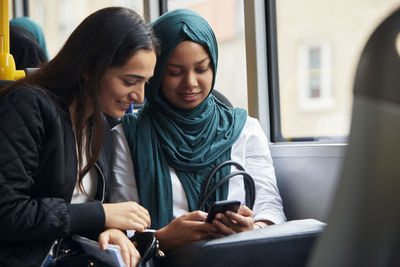 Female friend looking at cell phone in bus