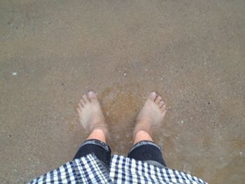 Low section of man standing on beach