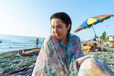 Portrait of young woman on beach against clear sky