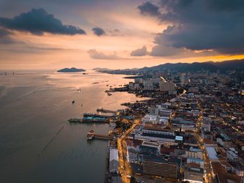 High angle view of sea and buildings against sky during sunset