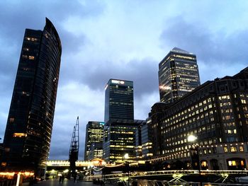 Low angle view of modern buildings against cloudy sky