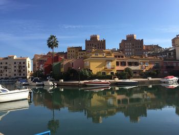 Sailboats in lake by buildings against sky in city