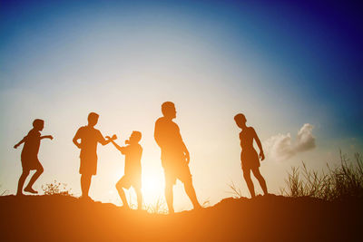 Silhouette people playing on field against sky during sunset