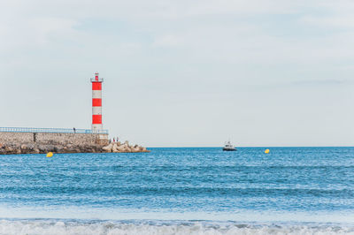 Lighthouse by sea against sky