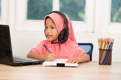 Portrait of girl sitting on table