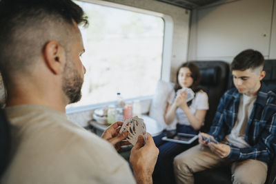 Father playing cards with son and daughter sitting in train