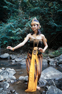 Portrait of young woman standing on rock