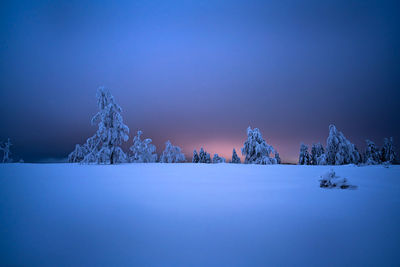 Snow covered landscape against blue sky