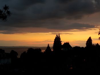 Silhouette trees and buildings against sky during sunset