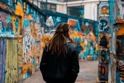 Rear view of woman standing against graffiti