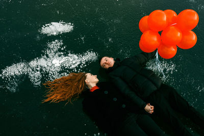 High angle view of couple with balloons lying on land