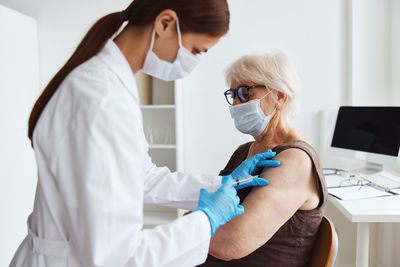 Doctor vaccinating senior woman at hospital