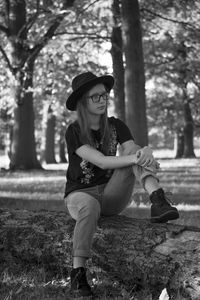 Full length of young woman sitting on fallen tree