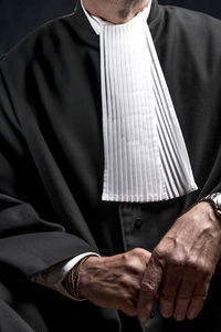 Midsection of lawyer standing against black background