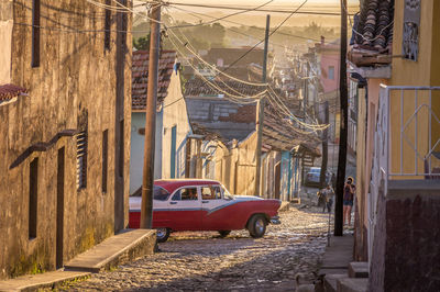 Car and people on road by buildings in city