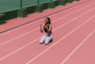 Black professional female athlete in sportswear rejoices with success in long-distance race on track