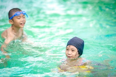 High angle view of siblings swimming in pool