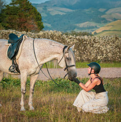 Lusitano mare, female dressage rider, saddle and bridle, helmet, on grass.