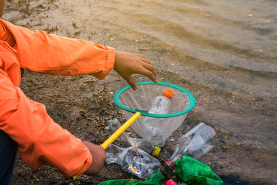 Low section of volunteer removing plastic bottles from lake