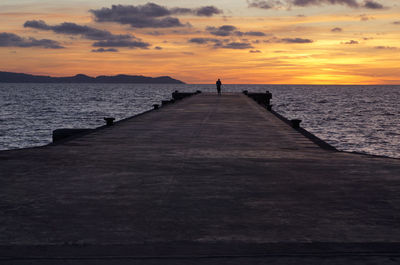 Pier over sea against sky during sunset