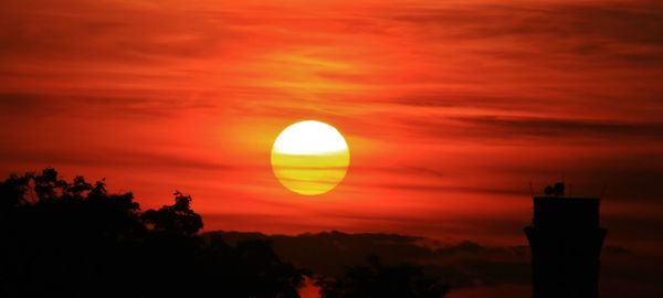 Silhouette trees against orange sky