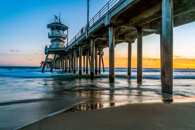 Pier on sea against sky at sunset