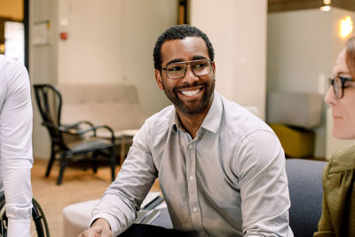 Smiling businessman looking away during sales meeting at work place