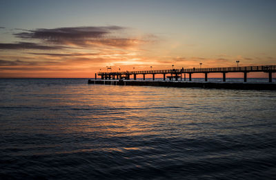 Pier over sea at sunset