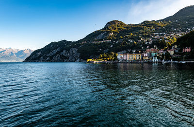 Scenic view of sea by mountain against sky