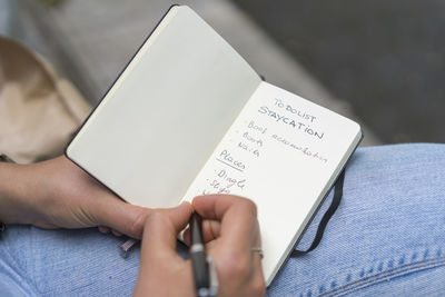 Close-up of woman writing in note pad