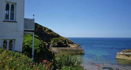 Scenic view of sea by buildings against clear blue sky