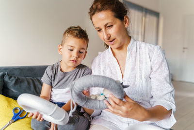 Cute boy holding baby sitting on sofa