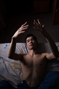 Portrait of shirtless young man lying in bed