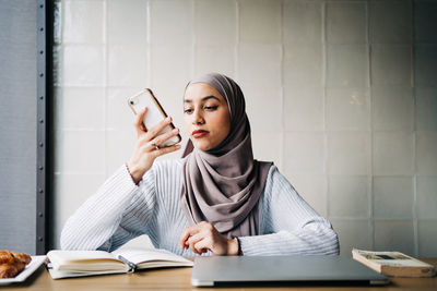 Young woman reading book while sitting on table