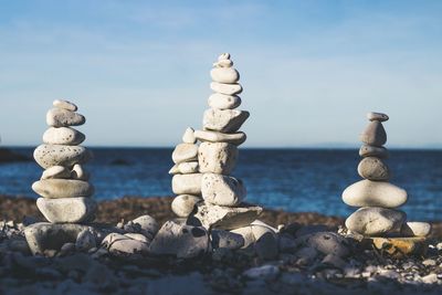 Stack of pebbles on beach against sky