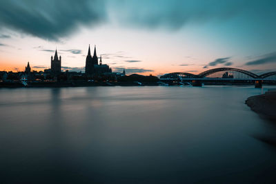 Bridge over river with buildings in background at sunset