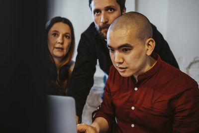 Male and female hackers working on laptop in startup company