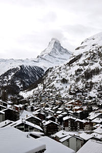 Aerial view of townscape and snowcapped mountain against sky