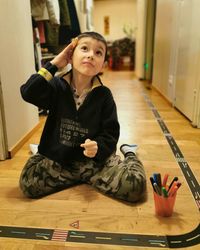 Boy looking away while sitting on floor at home