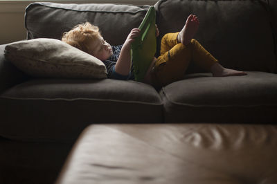 Toddler boy lays on couch watching his electronic during screen time