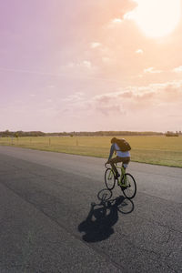 Man riding bicycle on road against sky