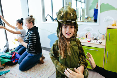 Girl smiles for the camera while wearing a dinosaur costume at school