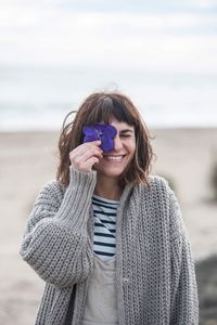 Smiling woman holding flower at beach