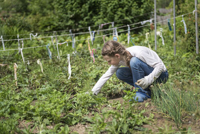 Full length of girl crouching by plants