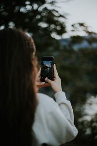 Rear view of woman photographing through smart phone