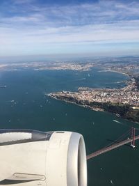 Cropped image of airplane engine flying over sea against sky