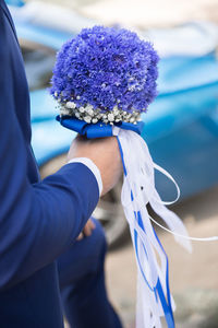 Midsection of bridegroom holding bouquet